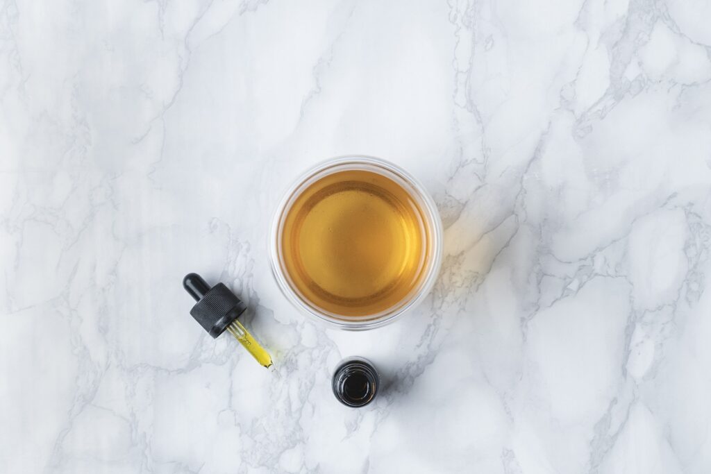 A bottle and bowl of CBD oil Yellowknife placed on a sleek marble table, exemplifying elegance and wellness