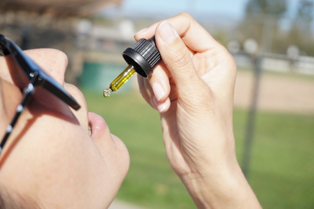 A girl holding a CBD oil dropper, poised to take a dropper full of CBD oil, representing CBD oil in PEI